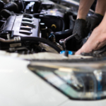 Repasovaný motor pripravený na montáž vedľa moderného auta na parkovisku.